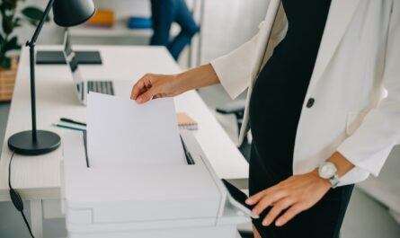 vue partielle d'une femme d'affaires enceinte utilisant une imprimante au bureau